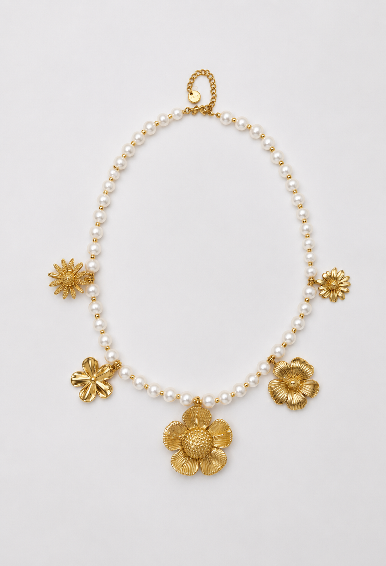 Collar de perlas blancas con cinco flores doradas de diseños distintos