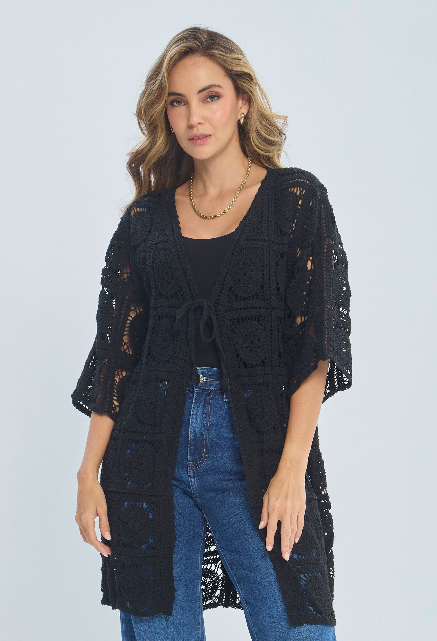Woman wearing a black crochet kimono cardigan over jeans and a black top