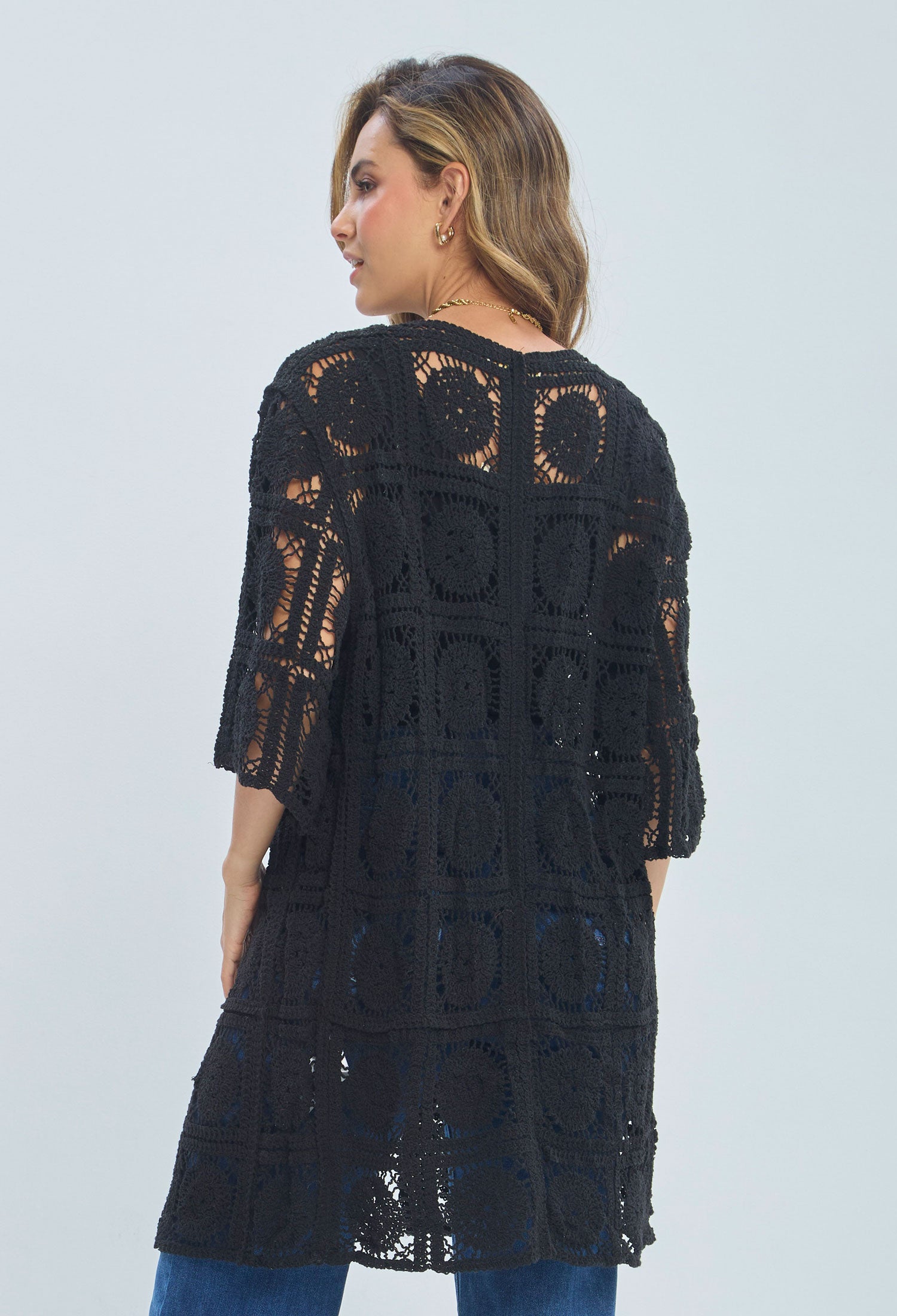 Woman wearing a black crochet tunic with geometric patterns and half sleeves