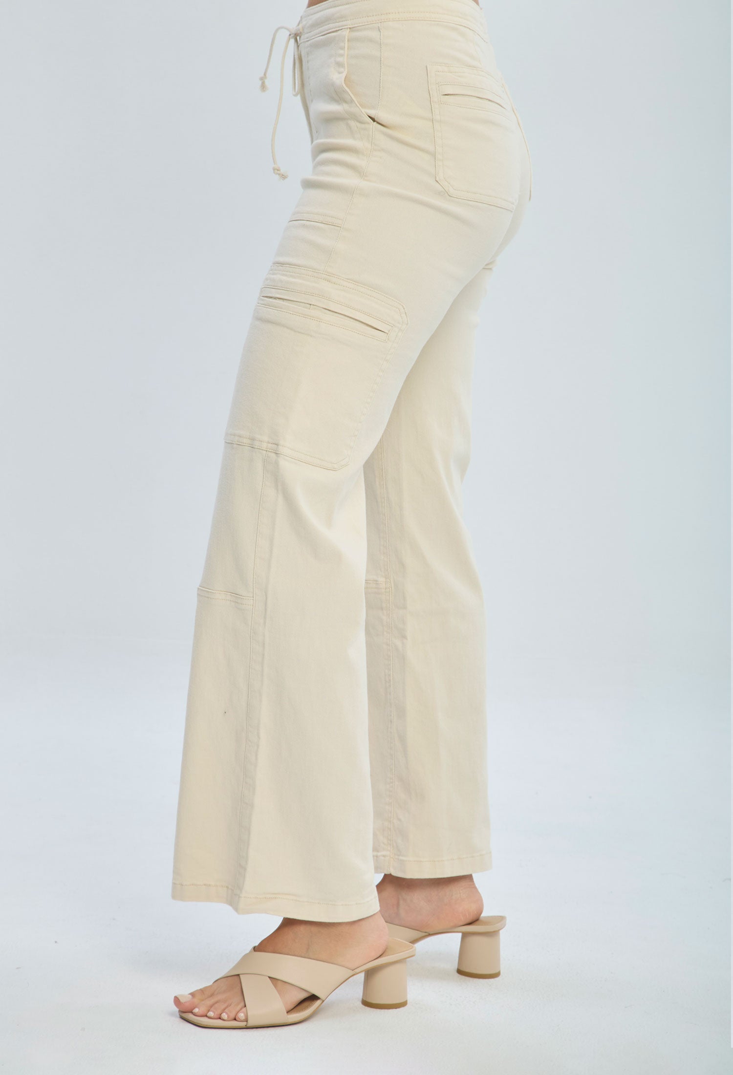Woman wearing high-waisted beige wide leg pants with cargo pockets and heeled sandals