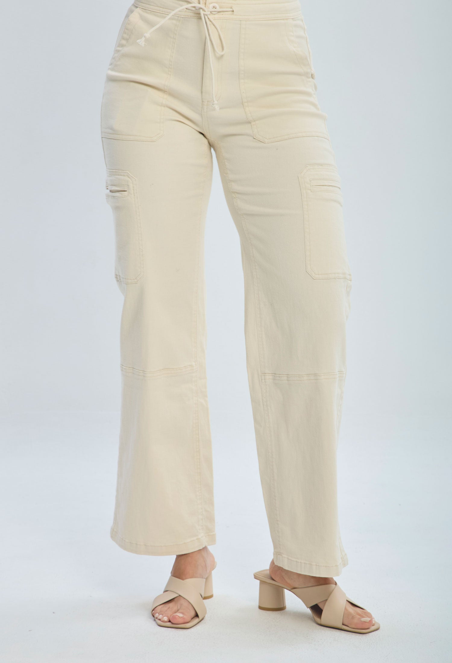 Woman wearing beige high-waisted wide leg pants with side pockets and heeled sandals