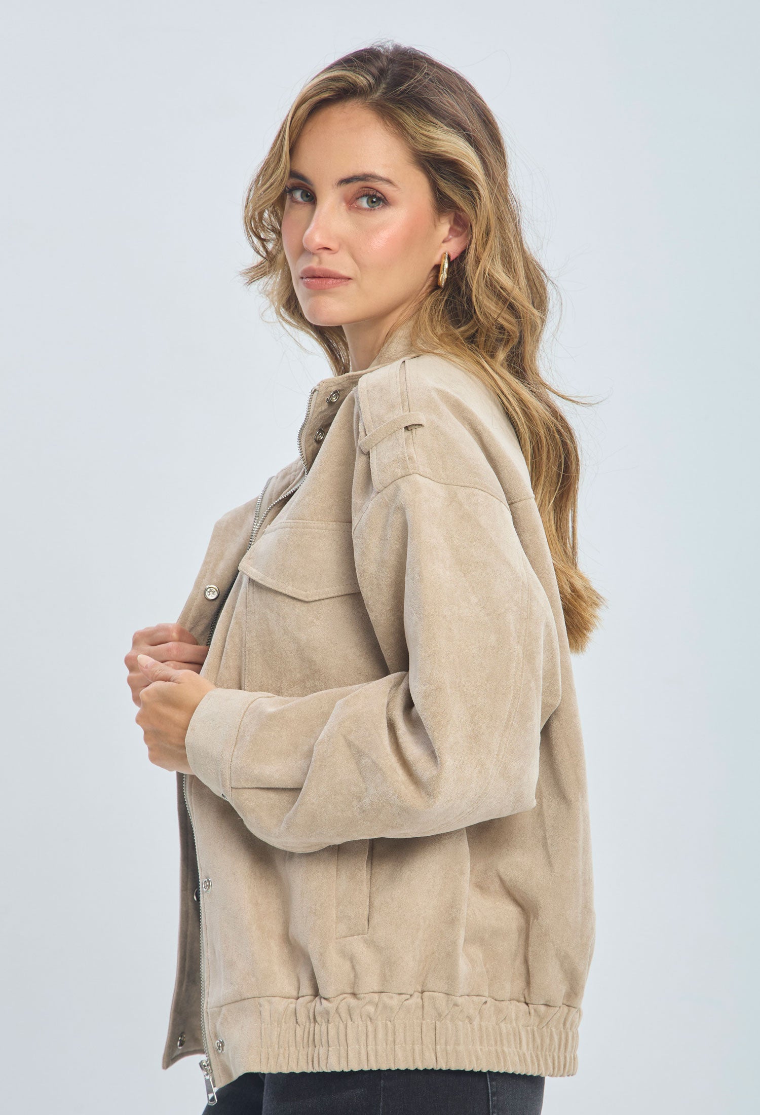 Woman modeling a beige suede jacket with long sleeves and front pockets, trendy outerwear