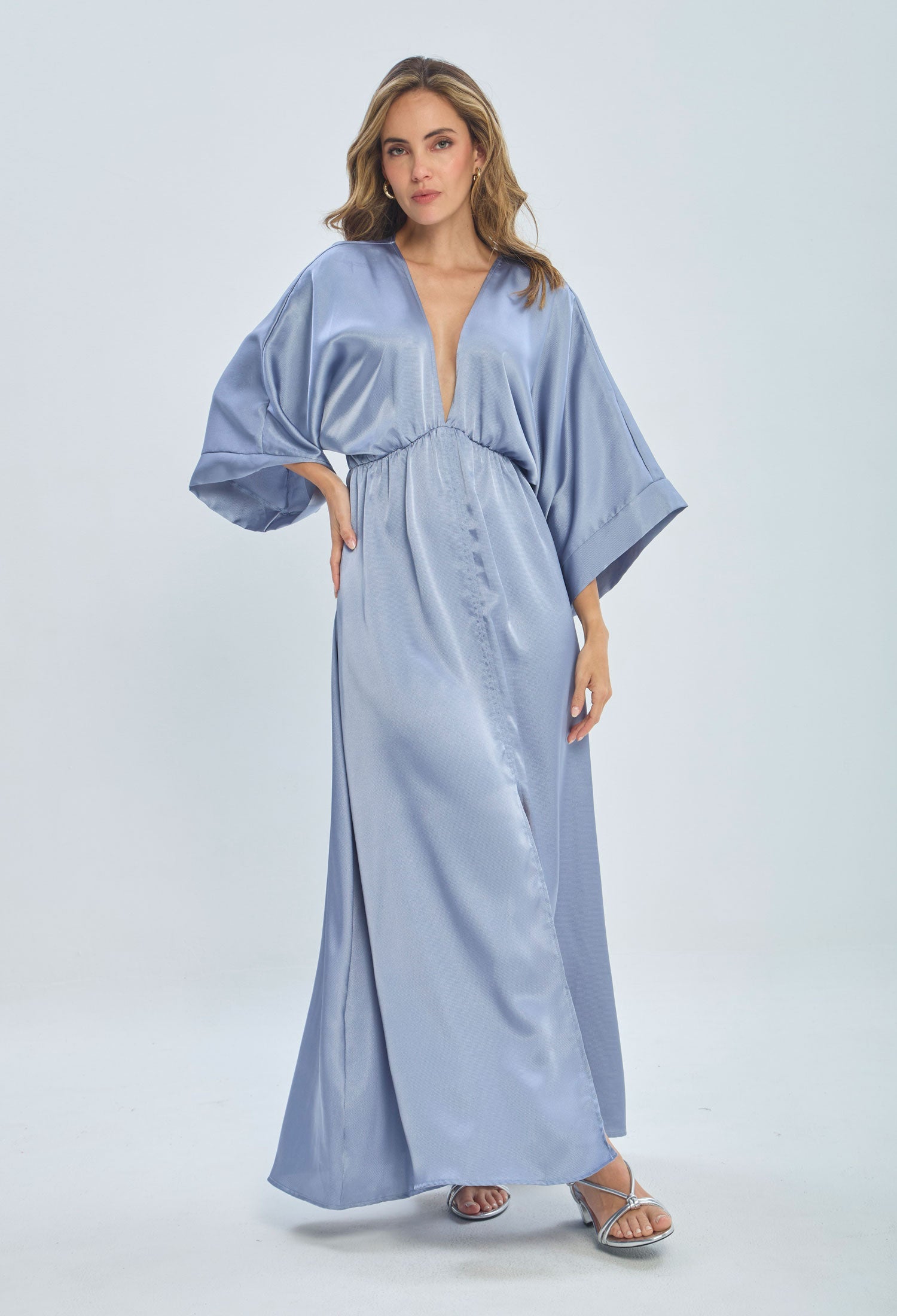 Woman modeling a satin light blue maxi dress with wide sleeves and deep V-neck