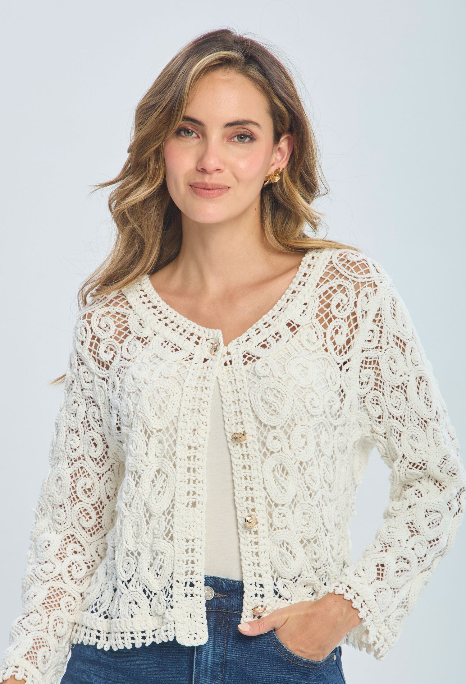 Woman wearing a white crochet lace cardigan with buttons and blue jeans, casual fashion