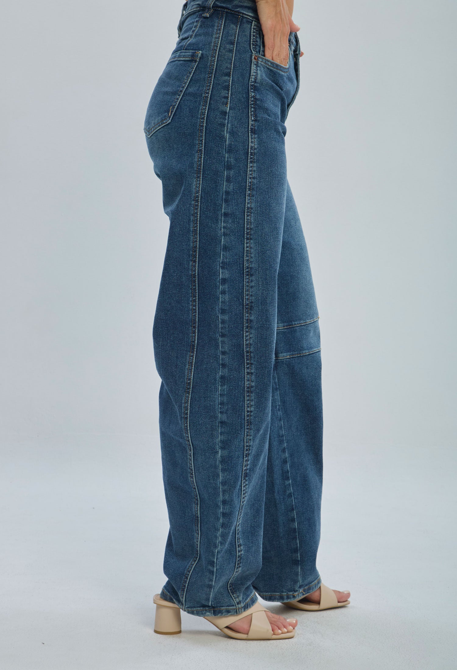 Woman wearing high-waisted wide leg blue jeans and beige heeled sandals