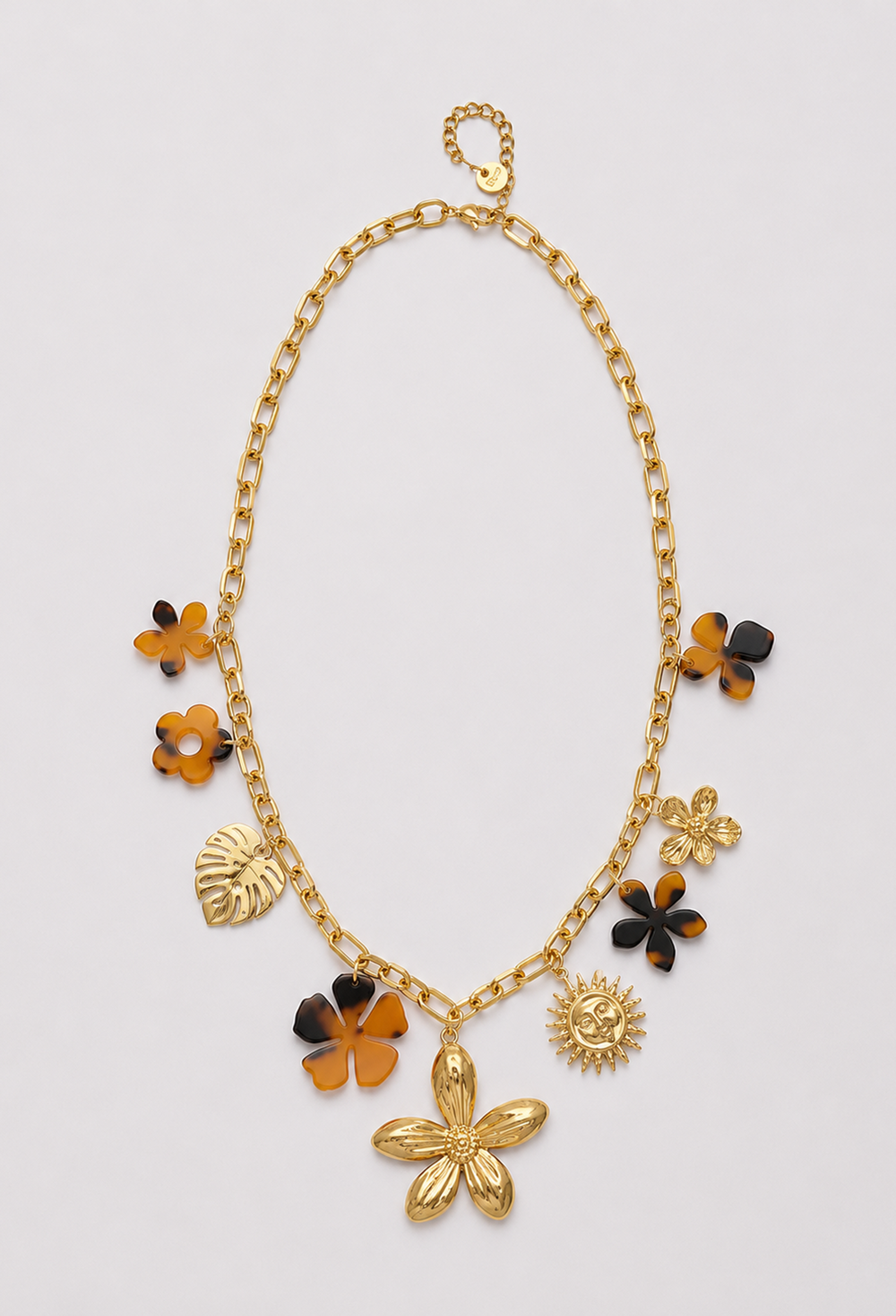 Collar de cadena dorada con dijes de flores carey, hoja de monstera y sol