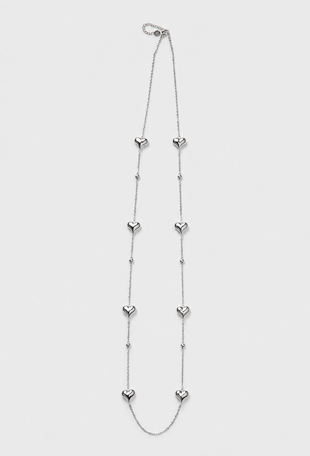 Collar largo de cadena fina plateada con corazones pulidos y esferas