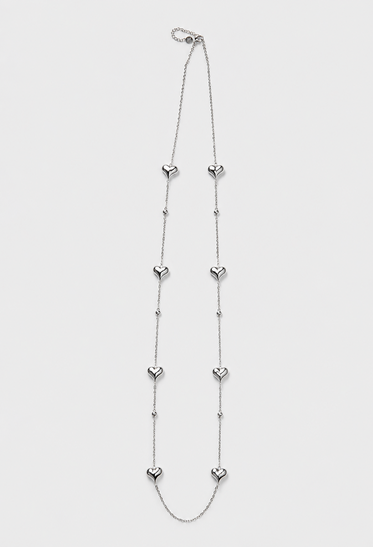 Collar largo de cadena fina plateada con corazones pulidos y esferas