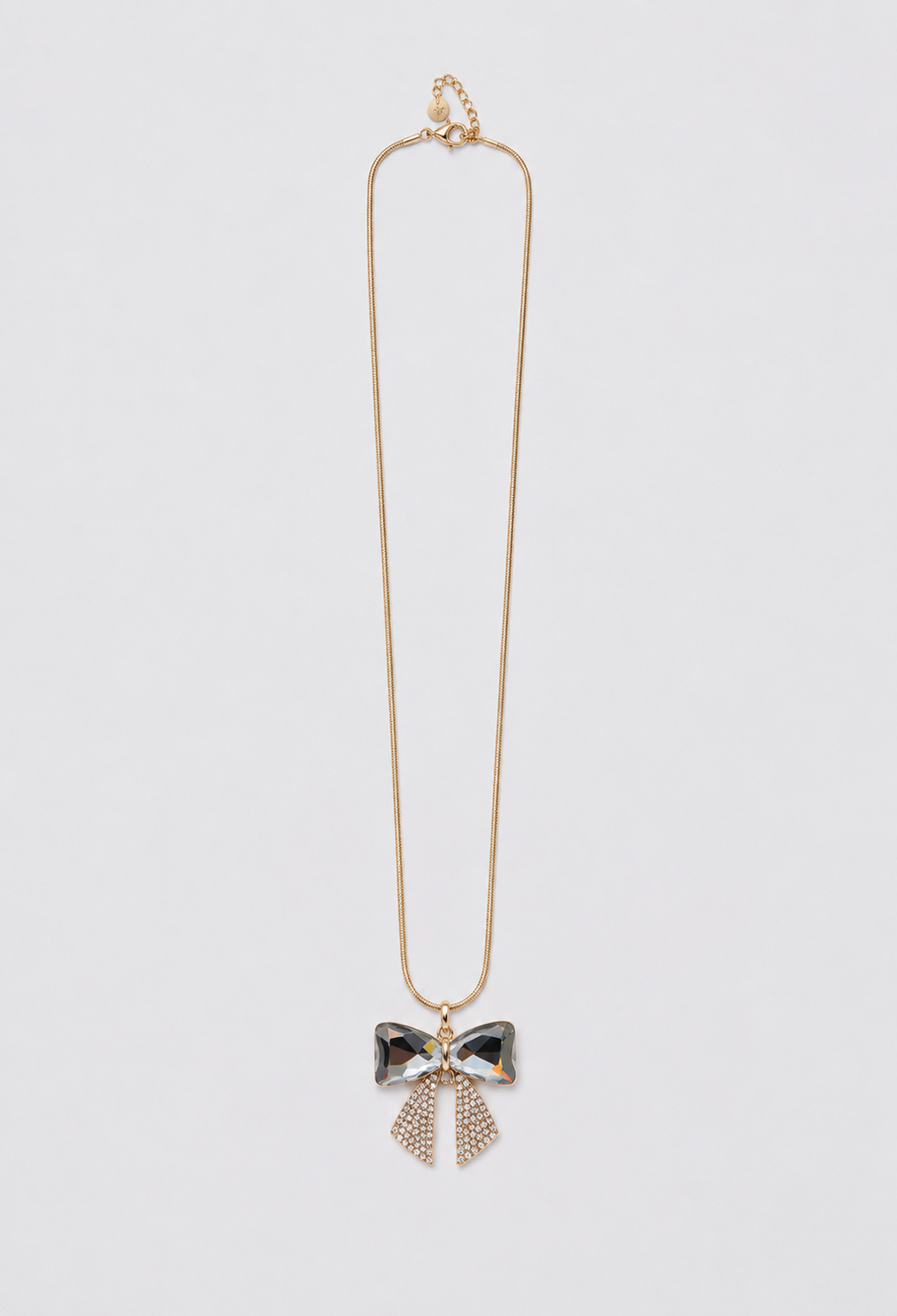 Collar largo dorado con dije de lazo en cristales facetados y pedrería