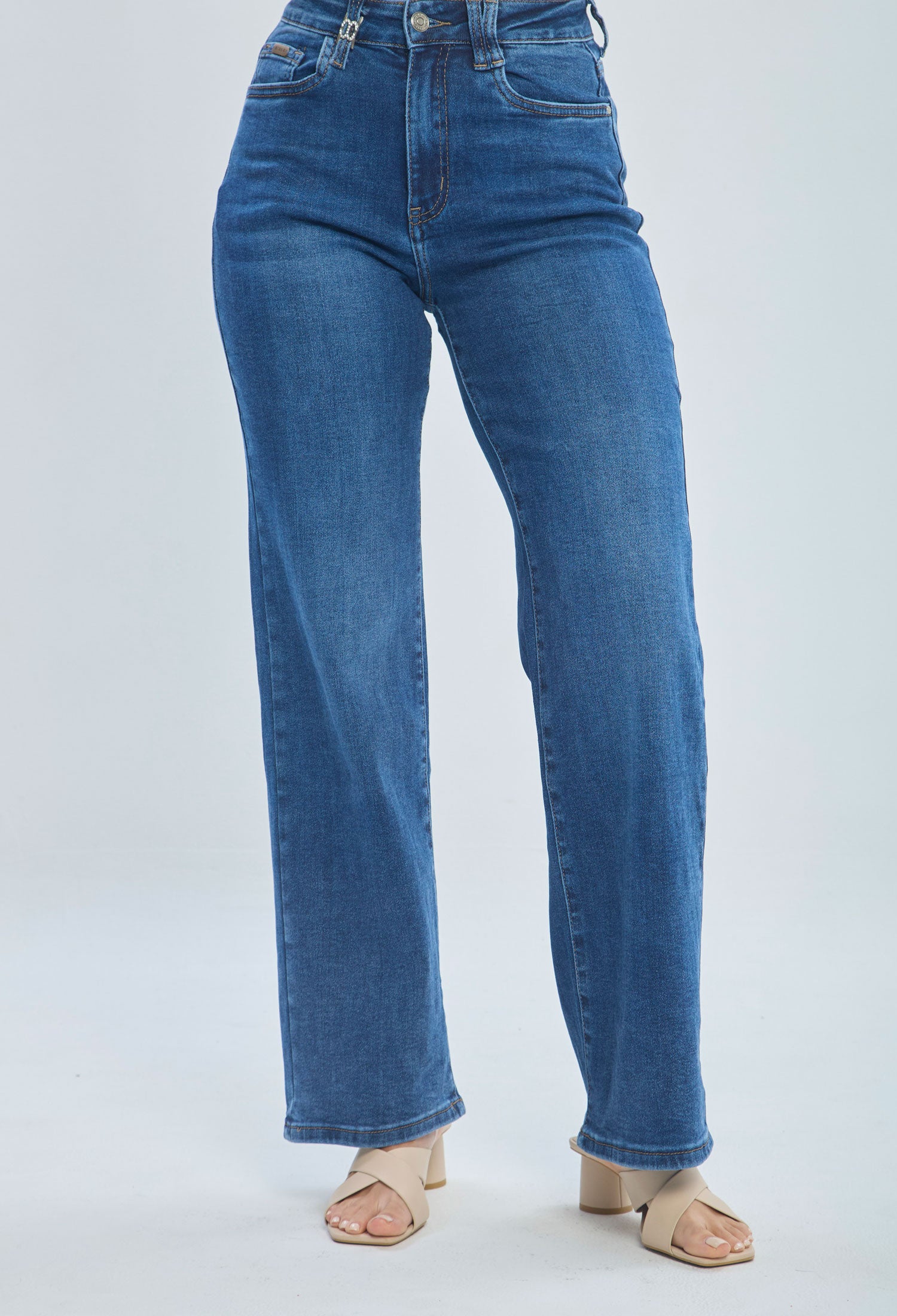 Woman wearing high-waisted straight-leg blue jeans and beige heeled sandals