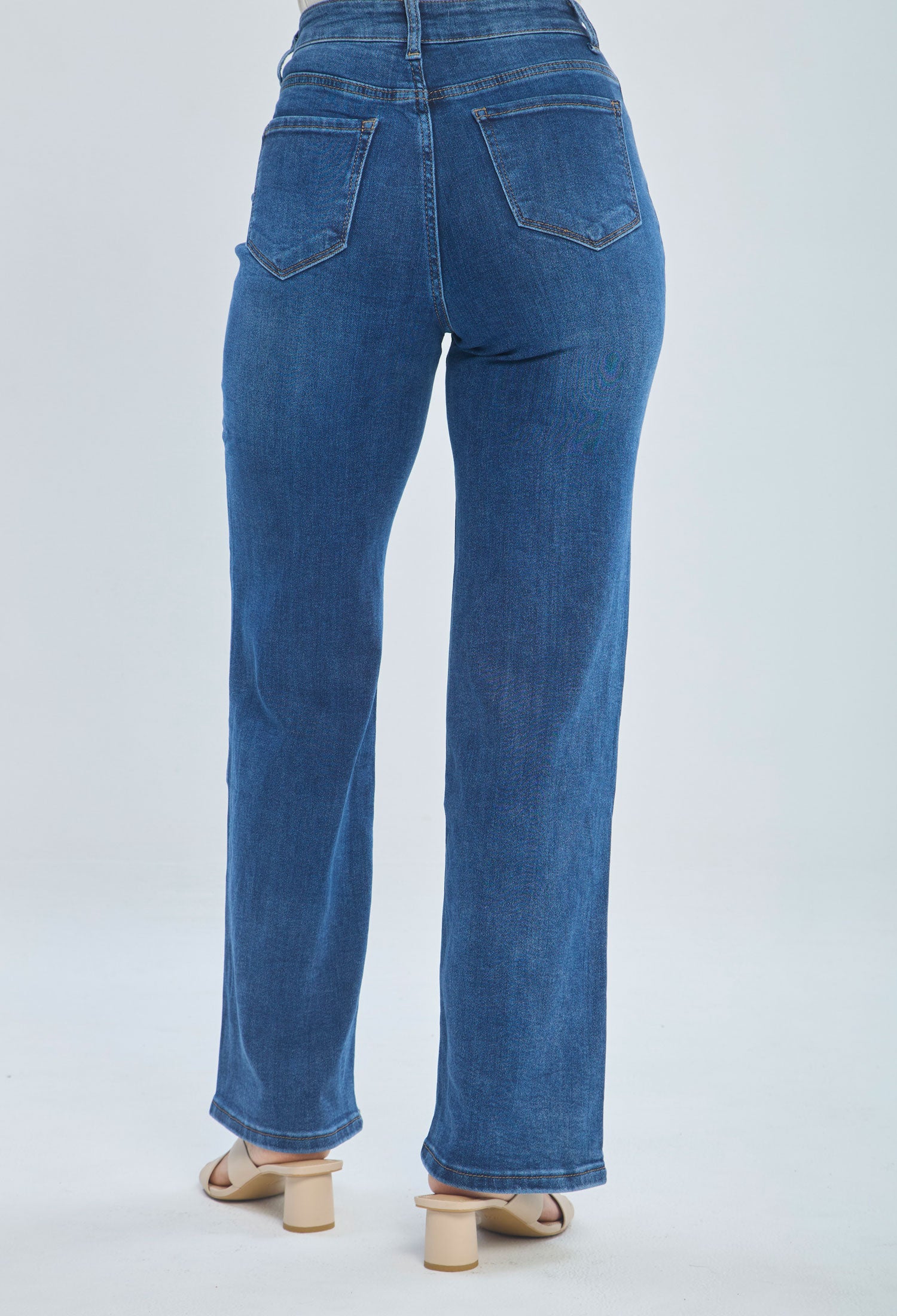 Back view of woman wearing high-waisted straight leg blue jeans and heeled sandals