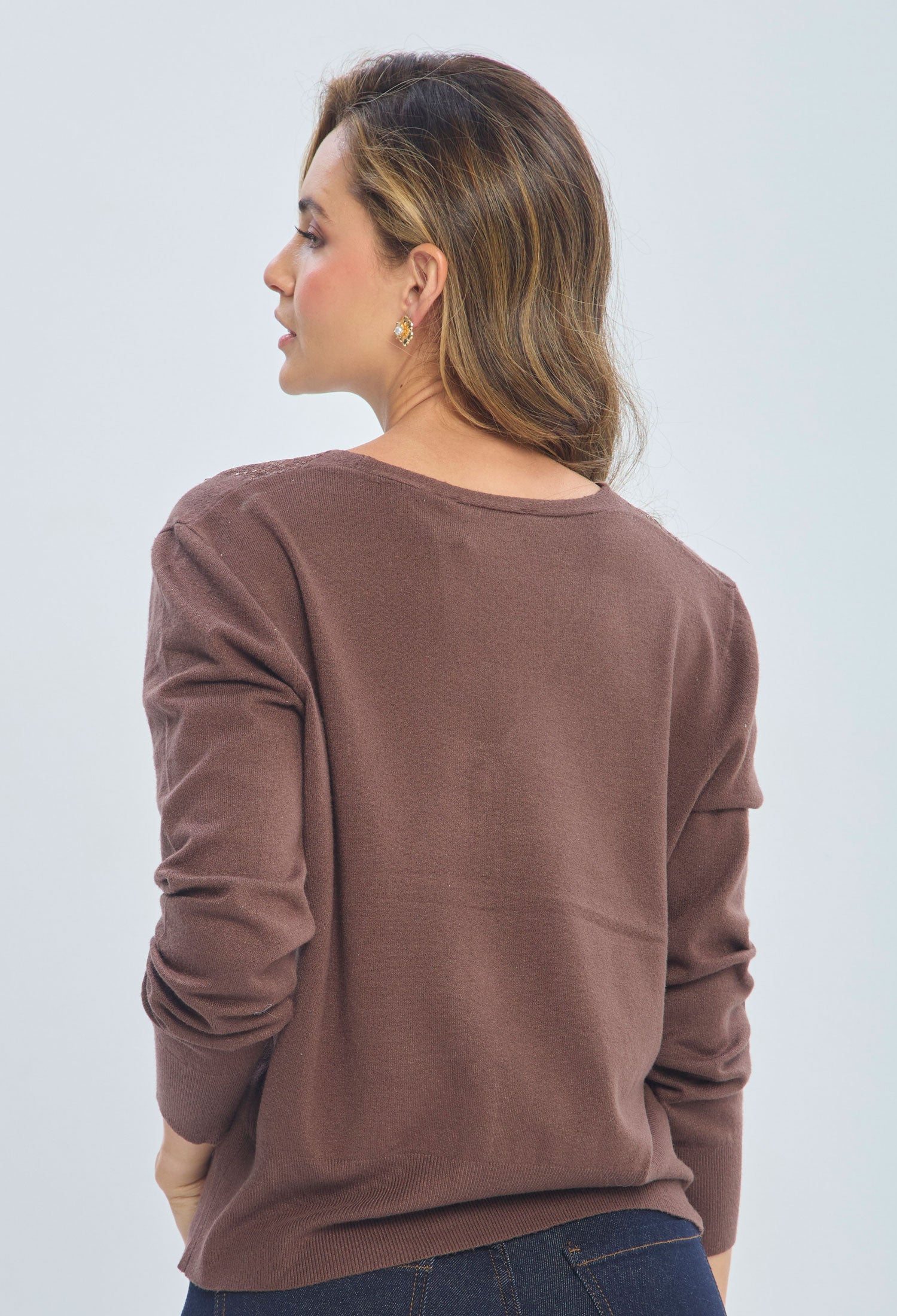 Woman wearing a brown long sleeve sweater and dark jeans, back view, fashion look