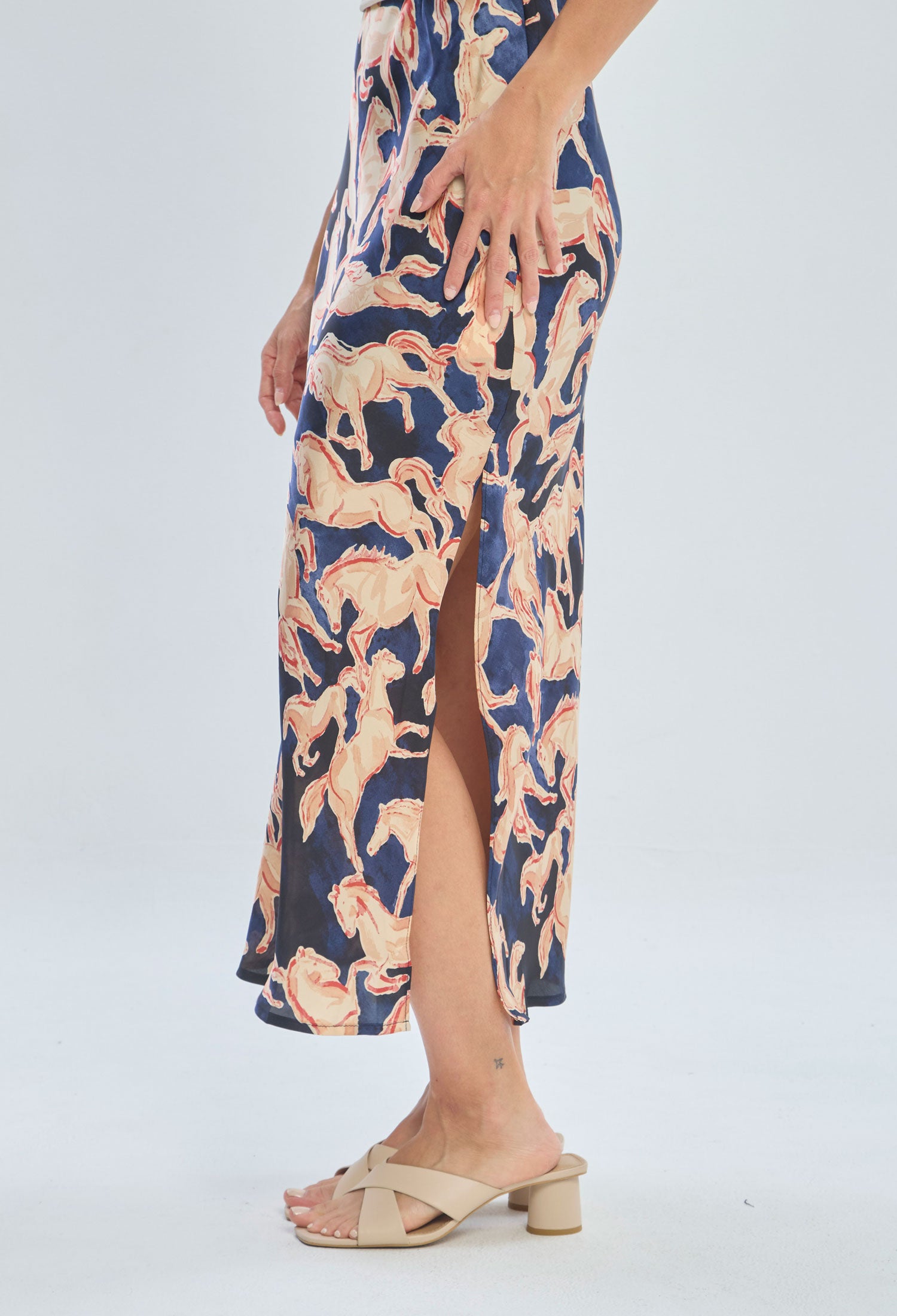 Woman wearing a colorful printed midi skirt with side slit and beige heeled sandals