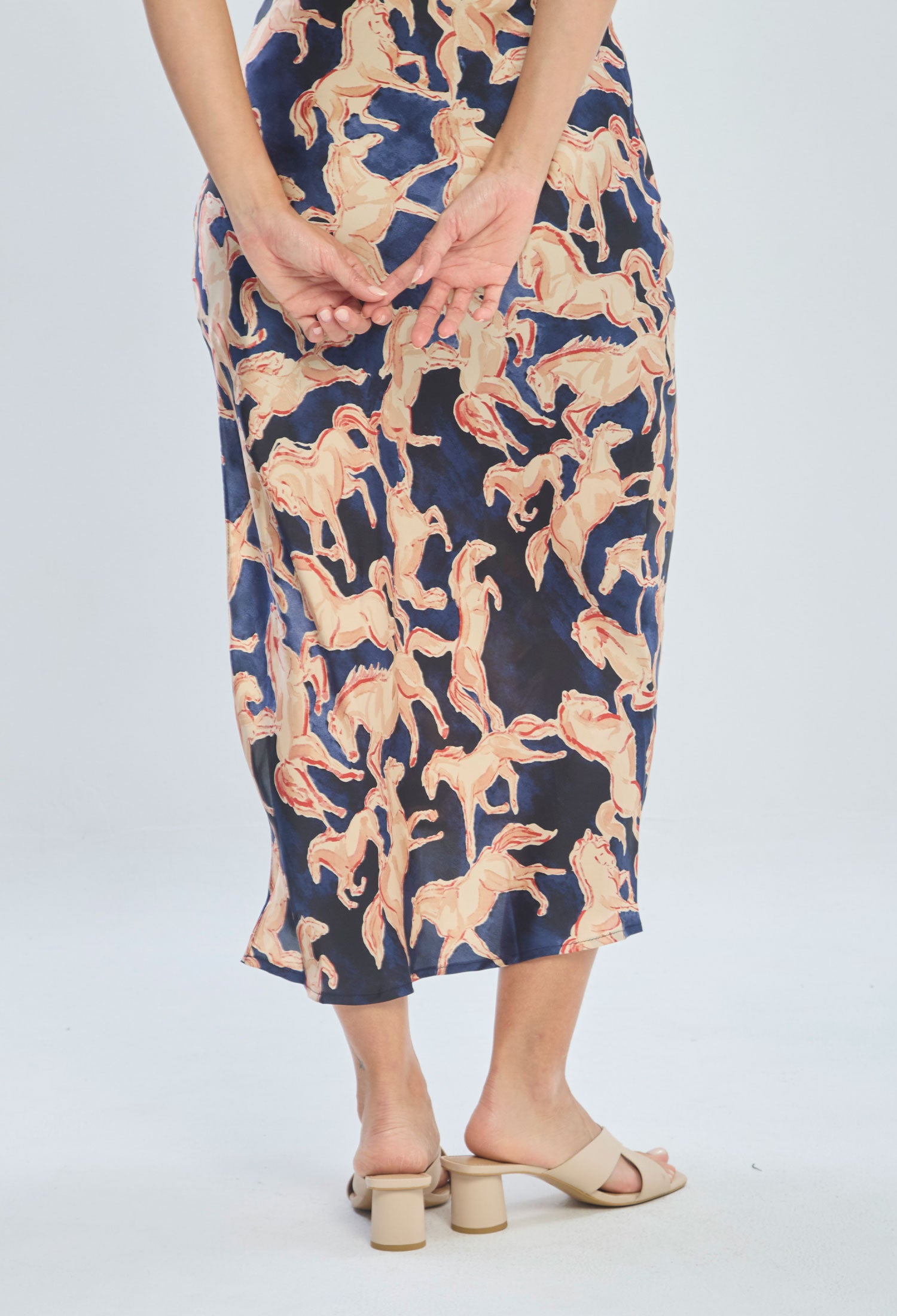 Woman wearing a midi skirt with beige horse print pattern and heeled sandals