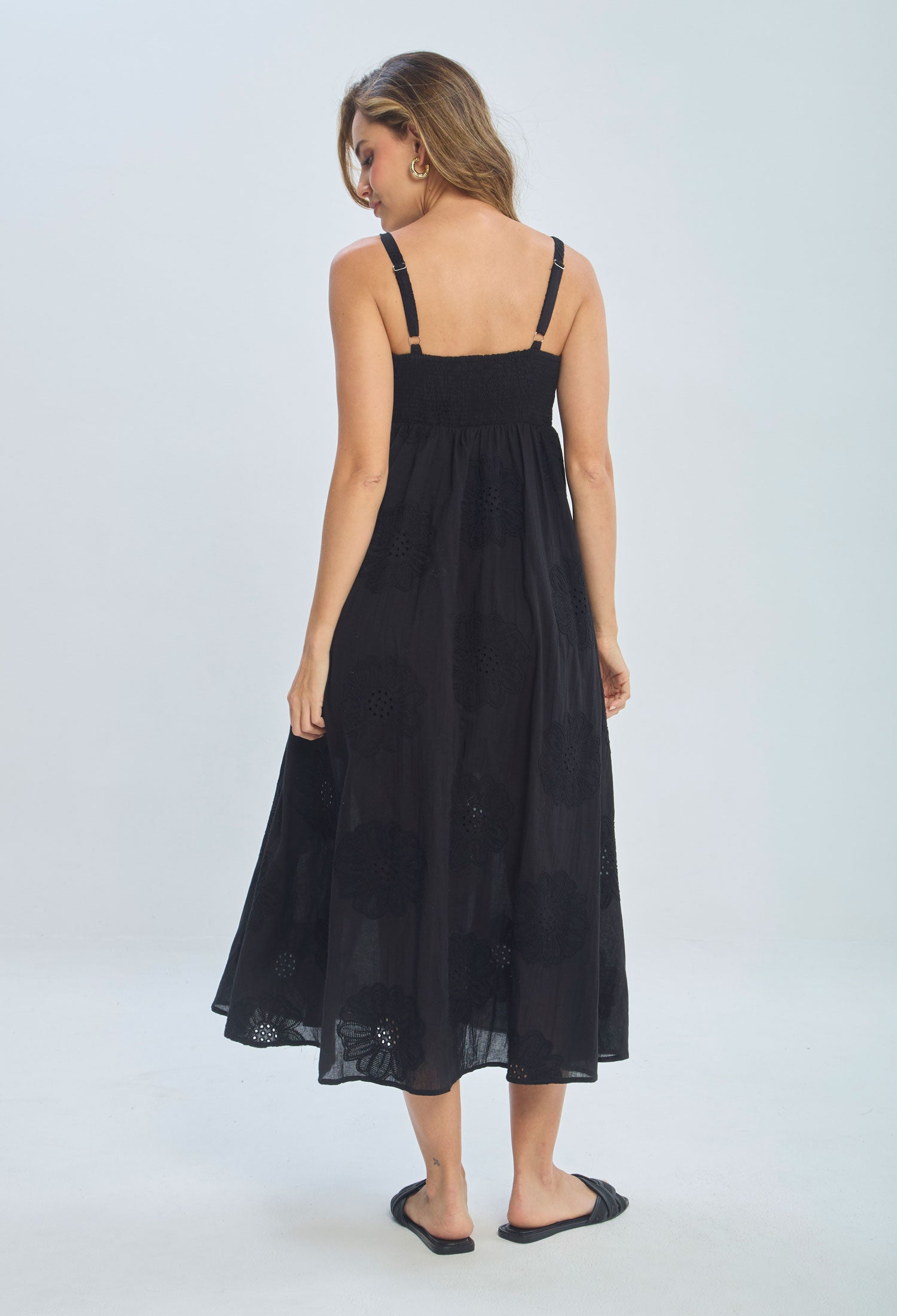 Woman wearing a black sleeveless midi dress with floral embroidery, viewed from back.