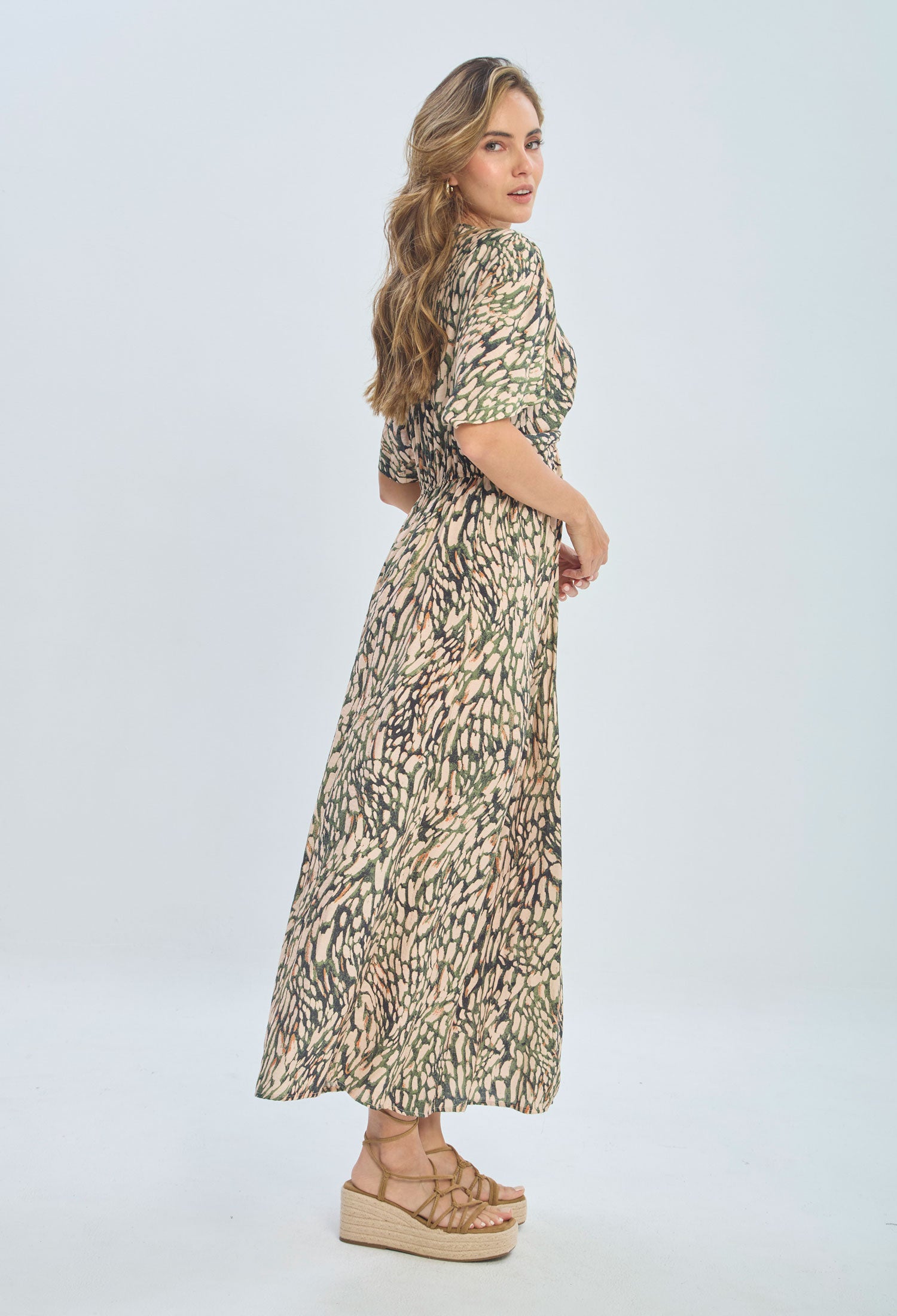 Woman wearing a patterned maxi dress with short sleeves and platform sandals