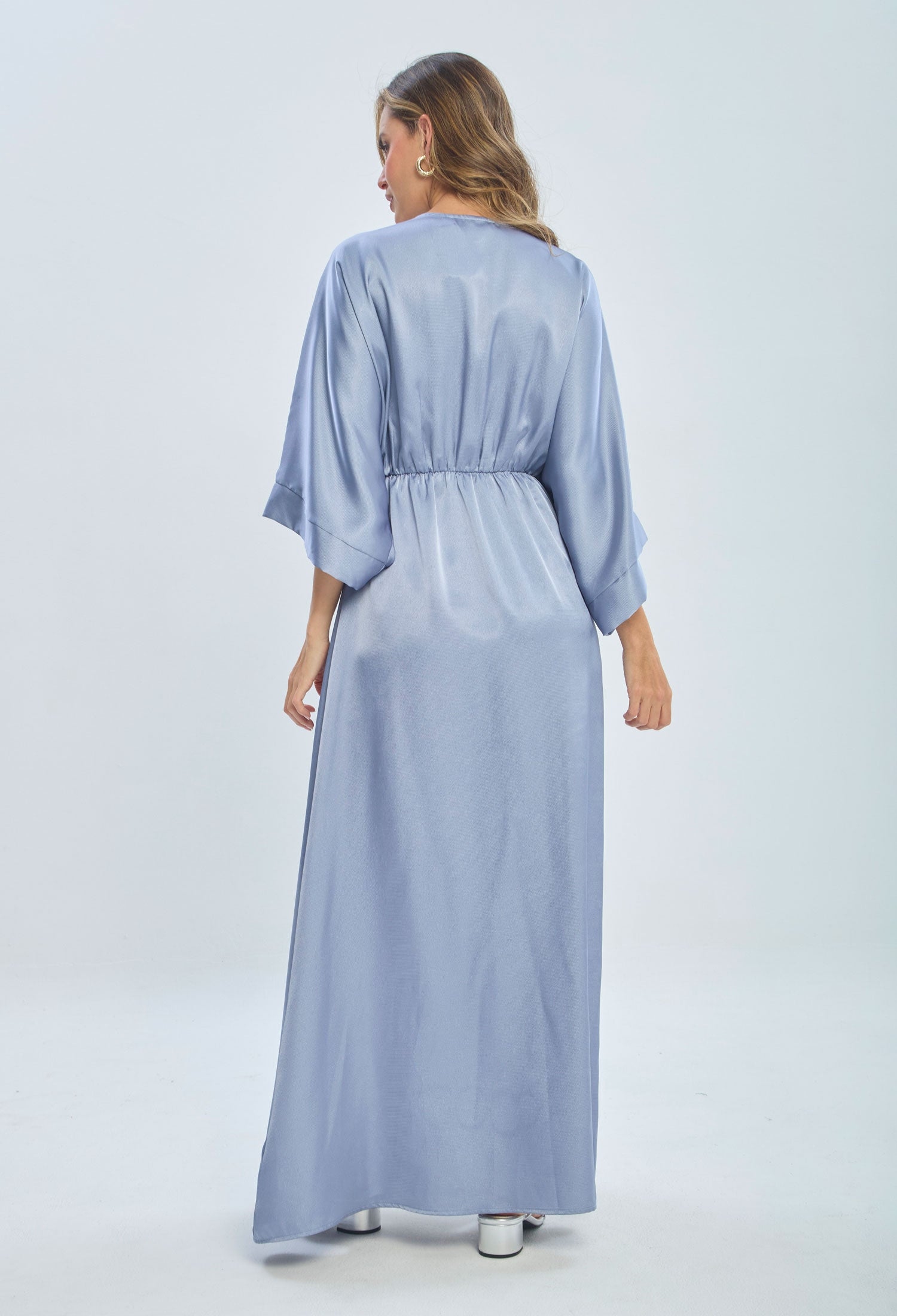 Woman wearing light blue satin maxi dress with loose sleeves, shown from the back
