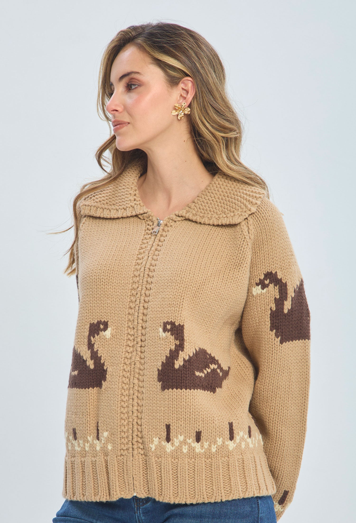 Woman wearing a beige knit cardigan with brown swan pattern and large collar