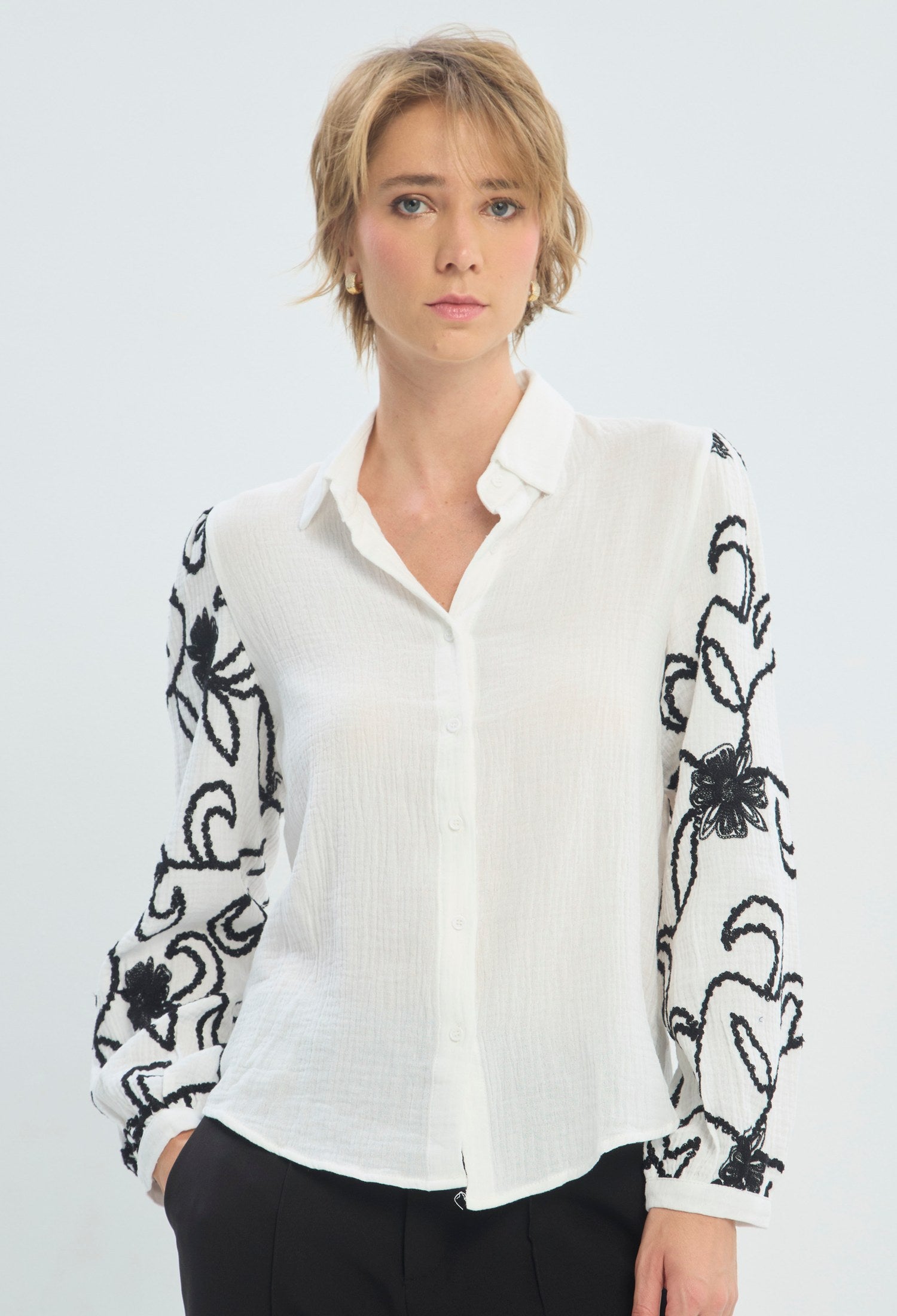 Blusa blanca manga larga con bordado floral negro en las mangas BYBLA